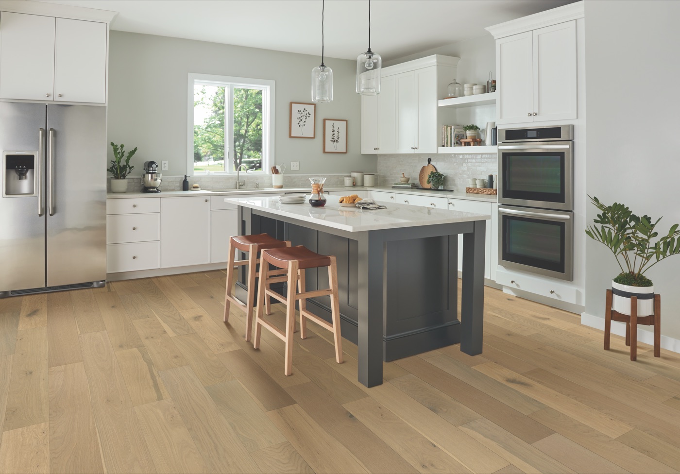 A bright kitchen with wide-plank oak flooring running the length of the room, white cabinets and a dark island.